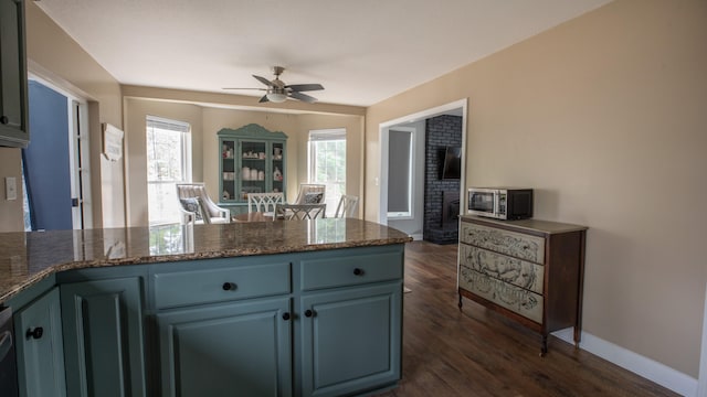 kitchen featuring dark stone counters, blue cabinets, ceiling fan, and dark wood-type flooring