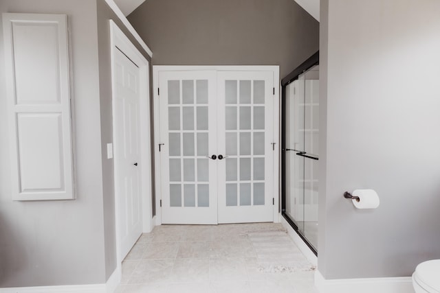 bathroom featuring tile patterned floors, french doors, a shower with shower door, and toilet