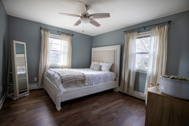 bedroom with a textured ceiling, dark hardwood / wood-style flooring, multiple windows, and ceiling fan