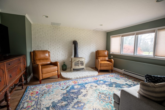 sitting room with brick wall, crown molding, a baseboard radiator, hardwood / wood-style floors, and a wood stove