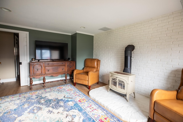 living area featuring a wood stove, crown molding, brick wall, and hardwood / wood-style flooring