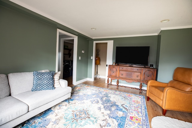 living room with washer / dryer, hardwood / wood-style floors, and crown molding