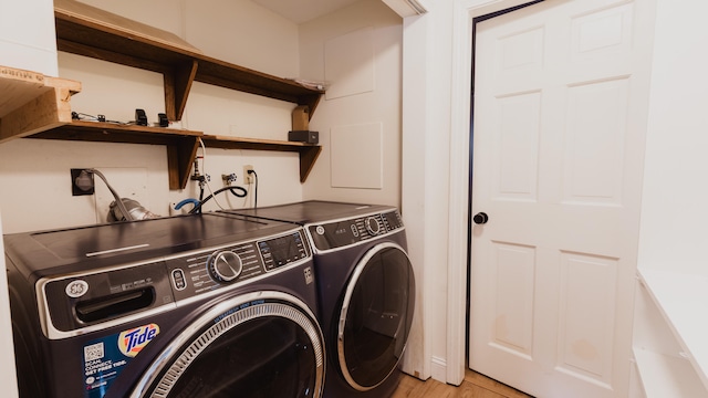 laundry room with washing machine and dryer and light wood-type flooring