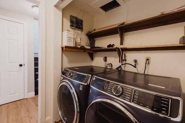 laundry area with light hardwood / wood-style flooring and washing machine and clothes dryer