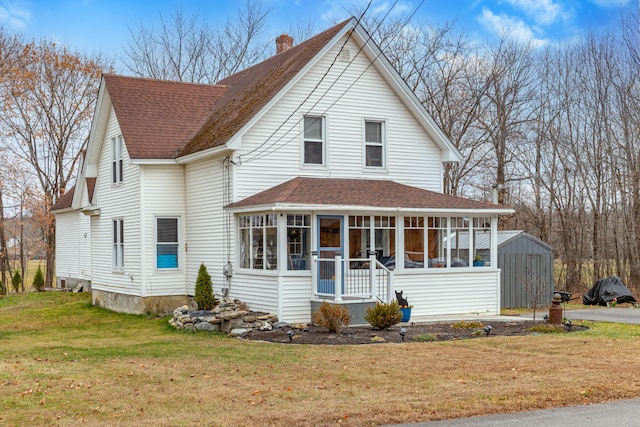 view of front of property with a sunroom, a storage shed, and a front yard