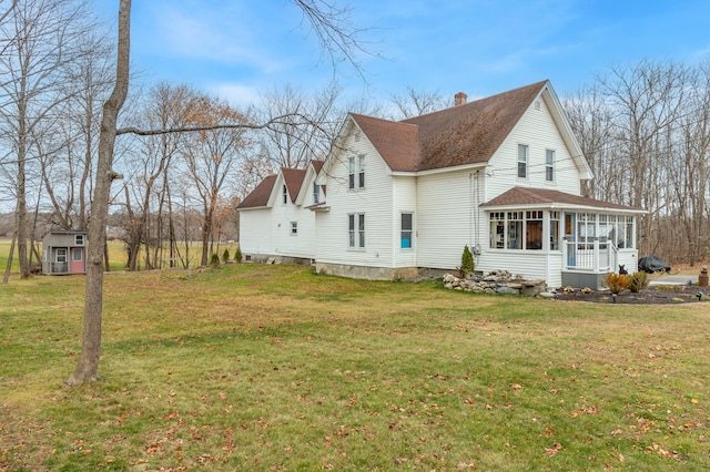 view of side of home featuring a yard, a storage shed, and a sunroom