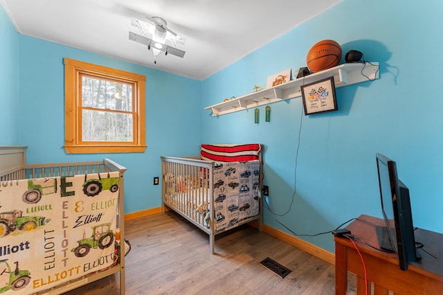 bedroom featuring hardwood / wood-style floors and a nursery area