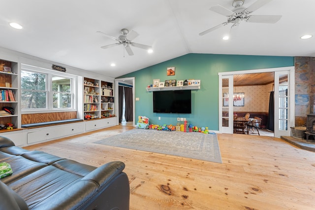 living room with vaulted ceiling, light hardwood / wood-style floors, a wood stove, and ceiling fan