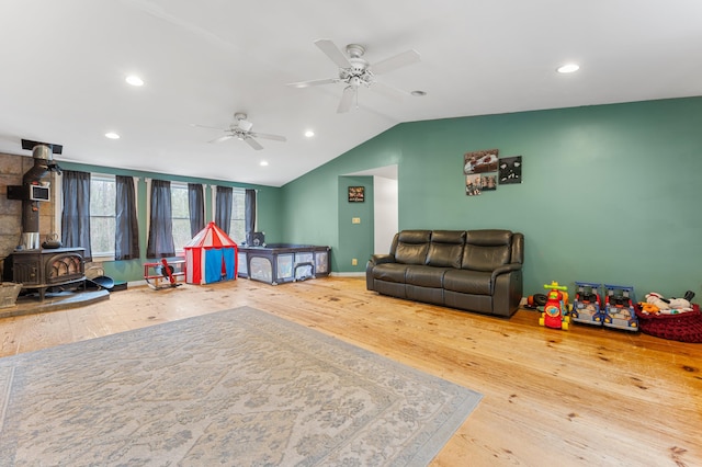 recreation room with a wood stove, ceiling fan, lofted ceiling, and hardwood / wood-style flooring