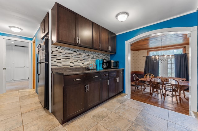 kitchen with crown molding, hanging light fixtures, decorative backsplash, stainless steel refrigerator, and a chandelier