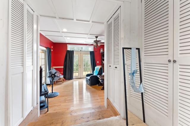 hall with french doors, coffered ceiling, and light wood-type flooring