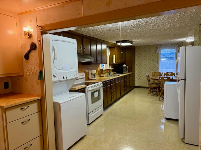 kitchen with a textured ceiling, white appliances, dark brown cabinetry, sink, and stacked washer / dryer