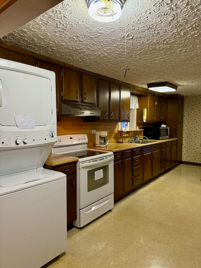 kitchen with dark brown cabinets, a textured ceiling, white range with electric stovetop, sink, and stacked washer and clothes dryer