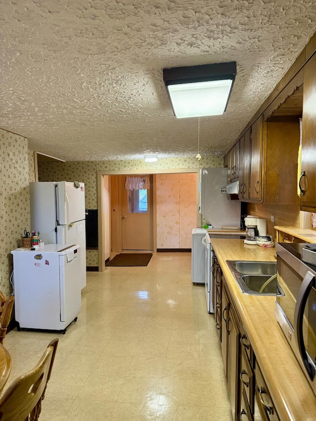 kitchen featuring a textured ceiling, sink, butcher block counters, and stainless steel appliances