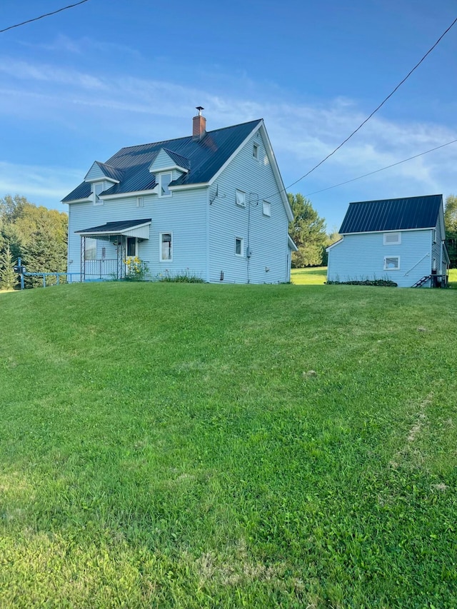 rear view of house featuring a yard and a chimney