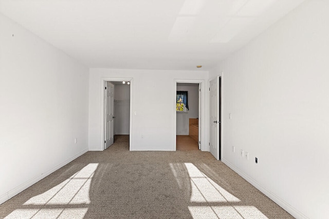 unfurnished bedroom featuring a spacious closet, light carpet, and a closet