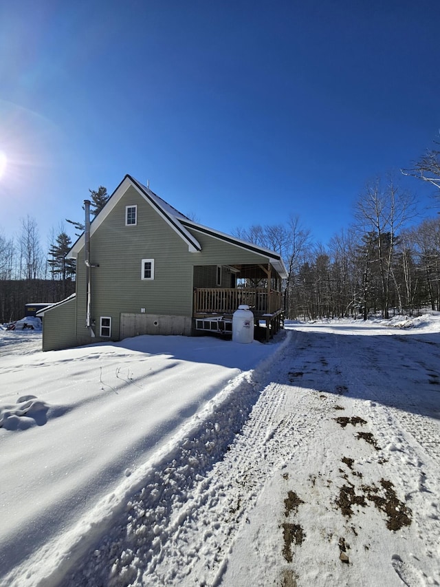 snow covered back of property featuring a wooden deck