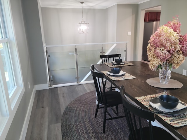 dining area with wood-type flooring, an inviting chandelier, and crown molding