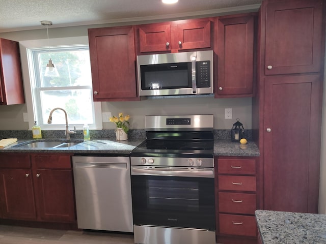 2 Old County Rd, Veazie, ME 04401 - kitchen featuring stainless steel appliances, a sink, dark brown cabinets, dark stone countertops, and hanging light fixtures