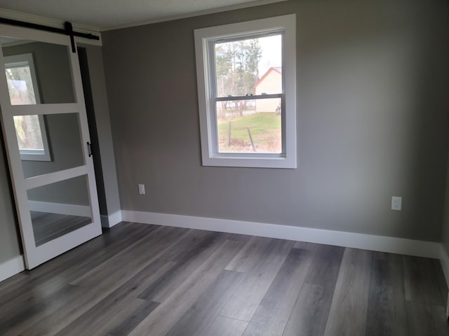 2 Old County Rd, Veazie, ME 04401 - empty room with a barn door, dark wood-type flooring, baseboards, and ornamental molding