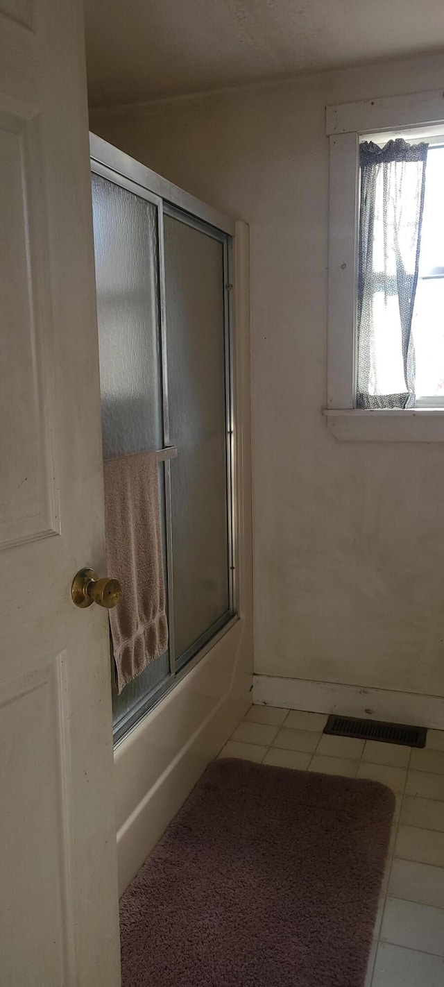 bathroom featuring shower / bath combination with glass door and tile patterned flooring