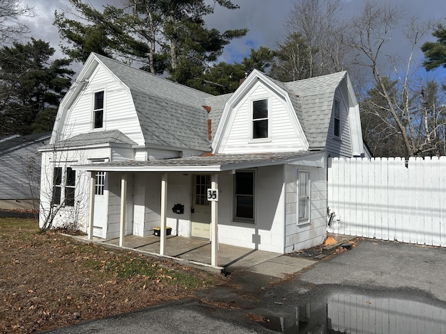 view of front of home featuring a shingled roof, fence, a patio, and a gambrel roof