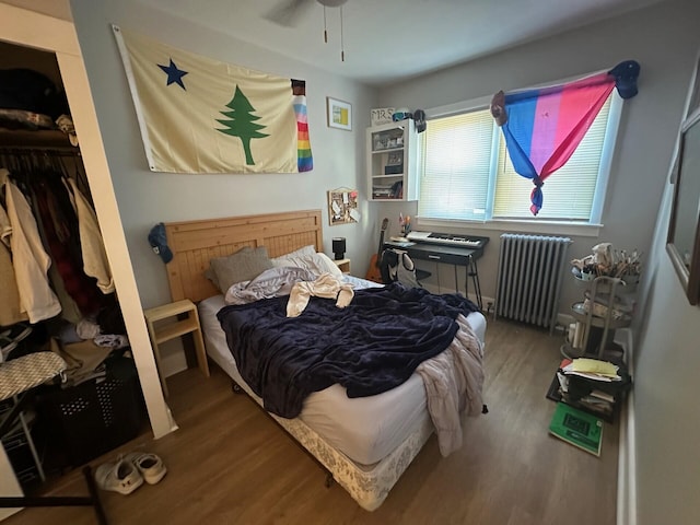 bedroom with radiator heating unit, ceiling fan, a closet, and hardwood / wood-style floors