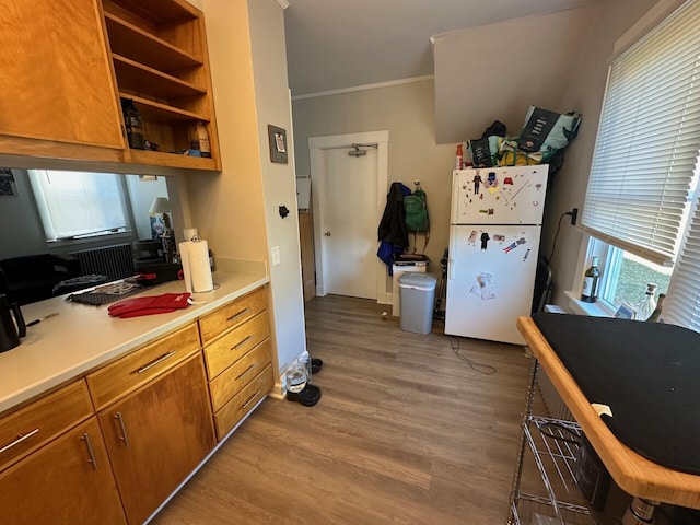 kitchen featuring wood-type flooring, white refrigerator, and crown molding