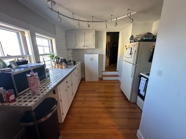 kitchen featuring white cabinets, light wood-type flooring, white appliances, and tile counters