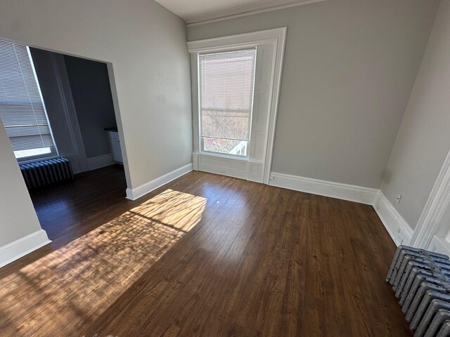 unfurnished room with dark hardwood / wood-style flooring and radiator