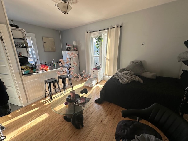 bedroom with light wood-type flooring and refrigerator