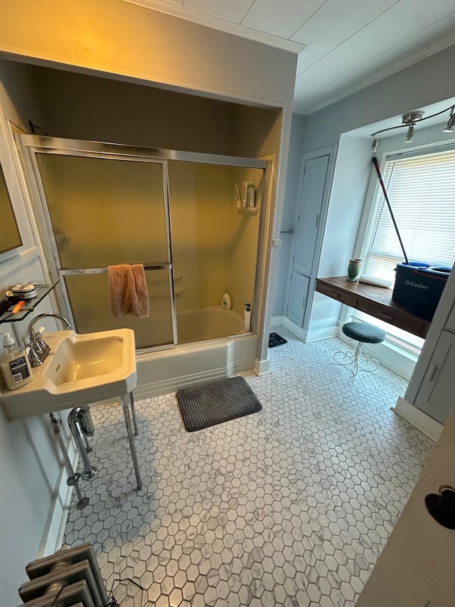 bathroom with sink, combined bath / shower with glass door, and crown molding