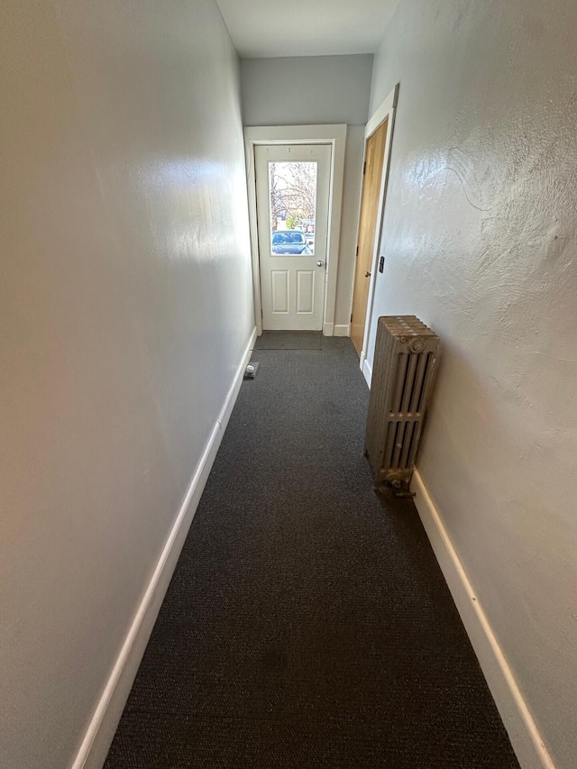 hallway with radiator and dark carpet