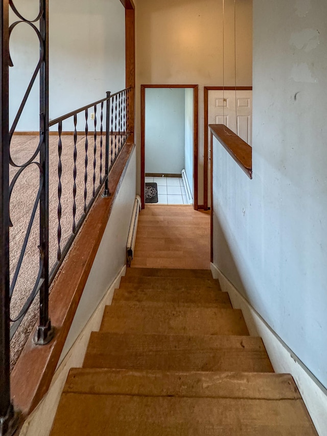 staircase with hardwood / wood-style floors and a baseboard radiator