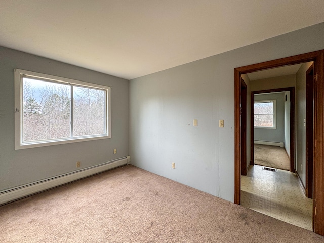 spare room featuring carpet floors, a healthy amount of sunlight, and a baseboard radiator