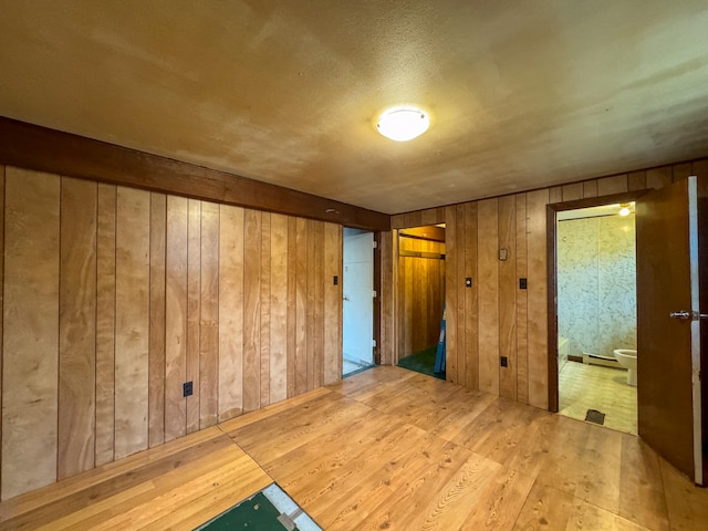 unfurnished room featuring wooden walls and hardwood / wood-style floors