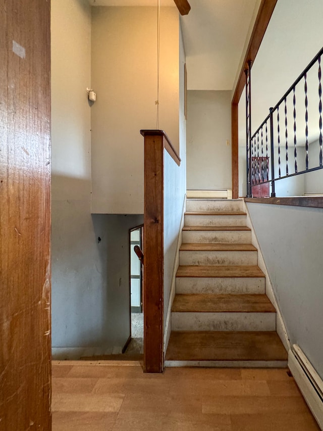 staircase with a baseboard heating unit and hardwood / wood-style flooring