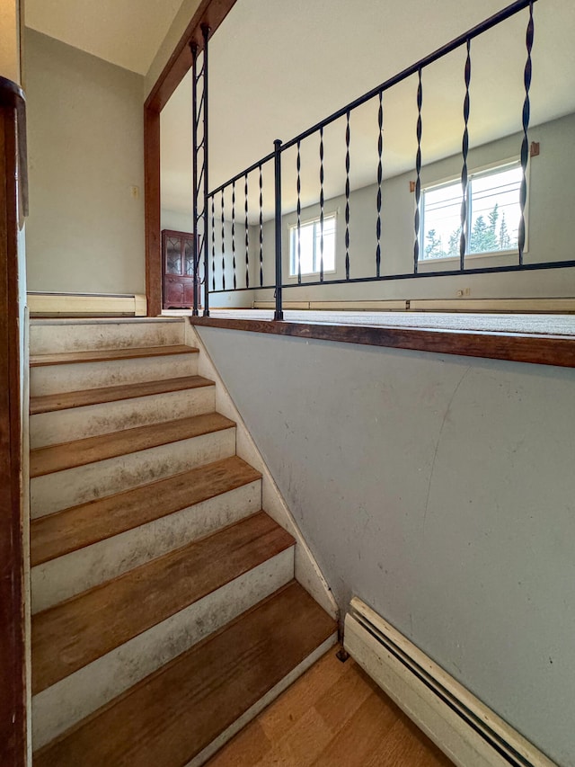 stairs with plenty of natural light, wood-type flooring, and a baseboard heating unit