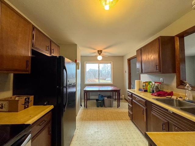 kitchen with ceiling fan, black fridge, range, and sink