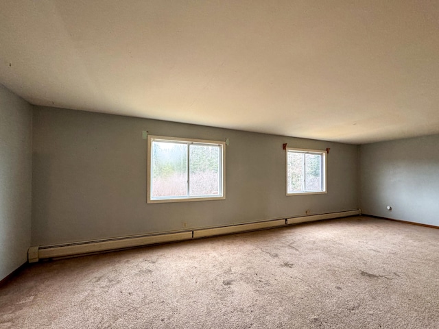 spare room with carpet flooring, plenty of natural light, and a baseboard heating unit