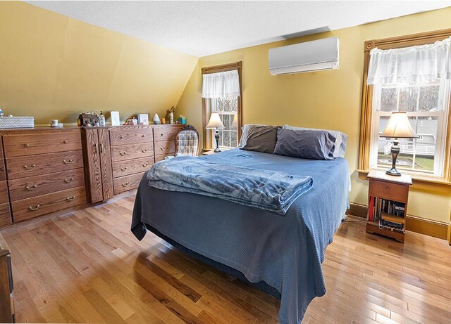 544 Main Rd N, Hampden, ME 04444 - bedroom with an AC wall unit, multiple windows, wood finished floors, and vaulted ceiling