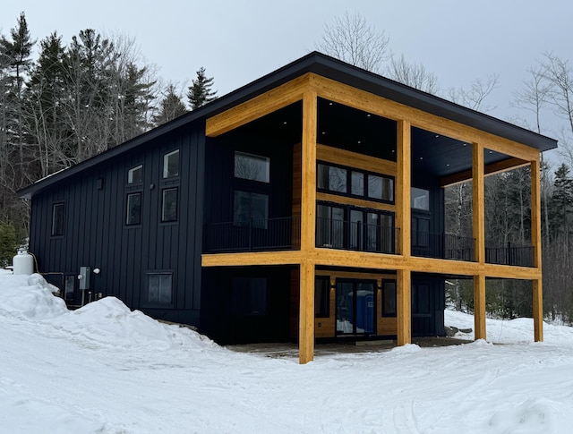 snow covered back of property featuring board and batten siding