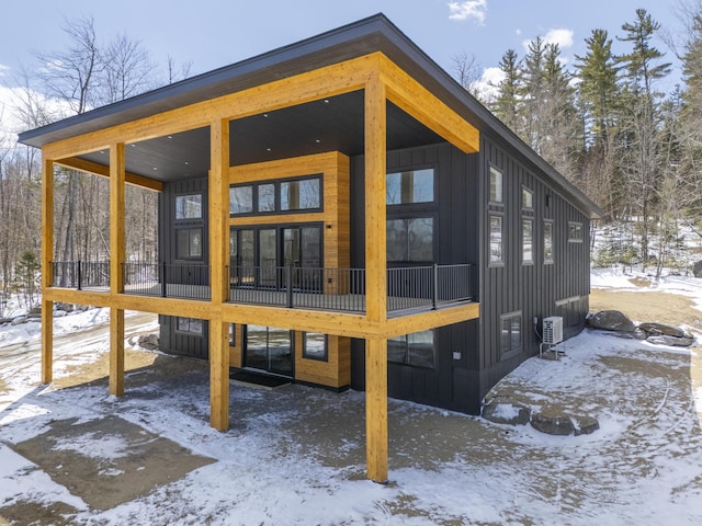 snow covered rear of property featuring board and batten siding