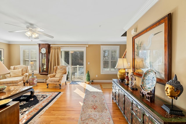 living room with baseboard heating, a wealth of natural light, crown molding, and light hardwood / wood-style flooring