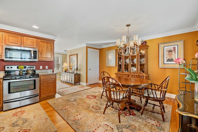 kitchen with a chandelier, crown molding, stainless steel appliances, and light wood-type flooring