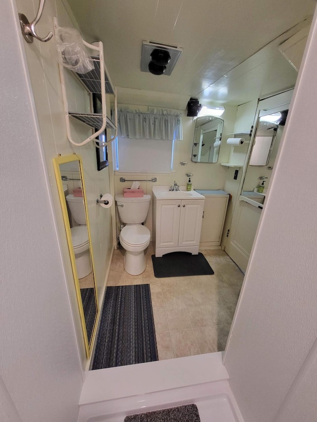 bathroom with tile patterned flooring, vanity, toilet, and a shower