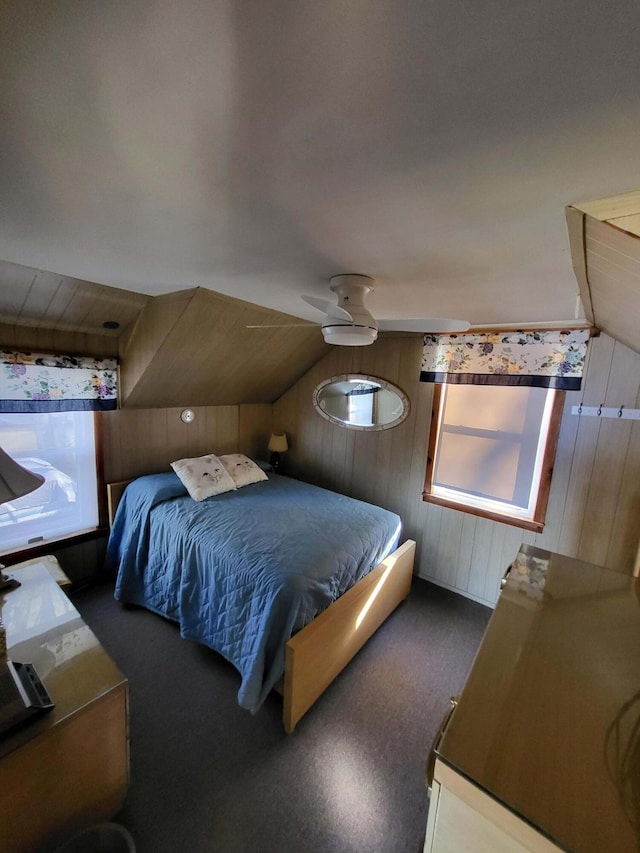 bedroom with ceiling fan, wood walls, and vaulted ceiling