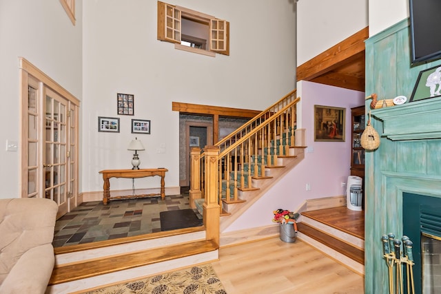 foyer with hardwood / wood-style floors, beamed ceiling, and a high ceiling