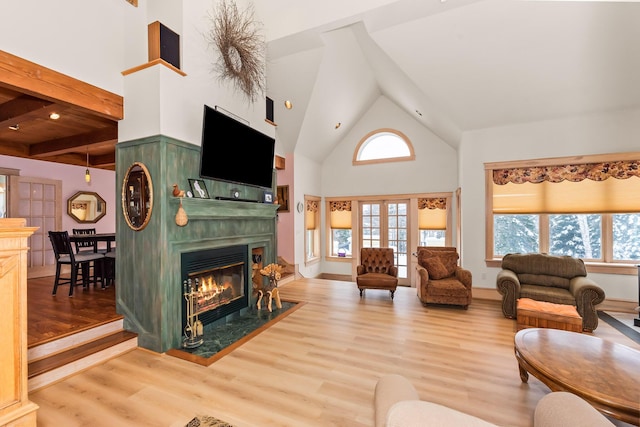 living room with beamed ceiling, light wood-type flooring, a fireplace, and high vaulted ceiling