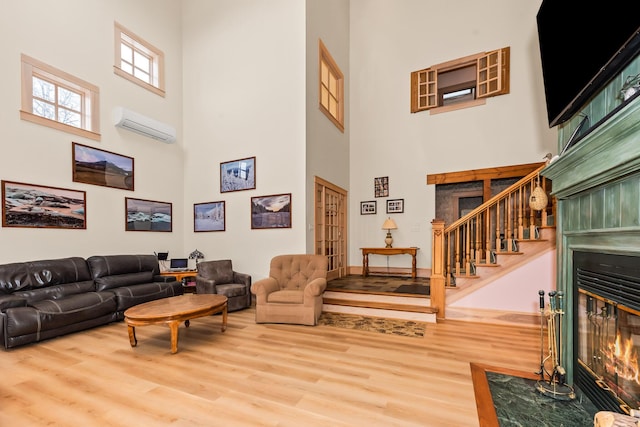 living room with a wall unit AC, wood-type flooring, and a high ceiling